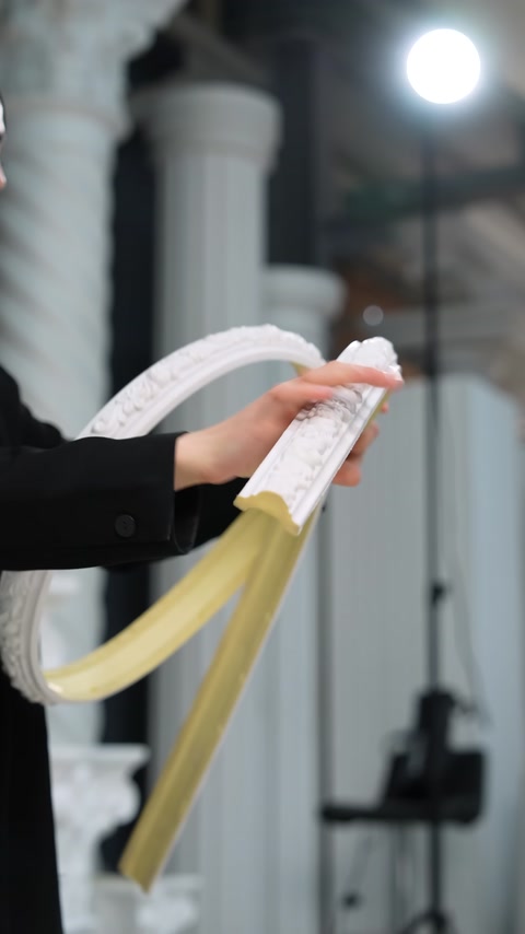 Primo piano di mani che confrontano una modanatura flessibile piegata e una modanatura dritta