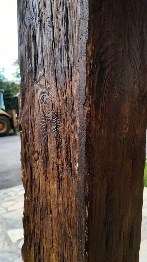 La superficie scura effetto legno della trave verticale viene esaminata da vicino