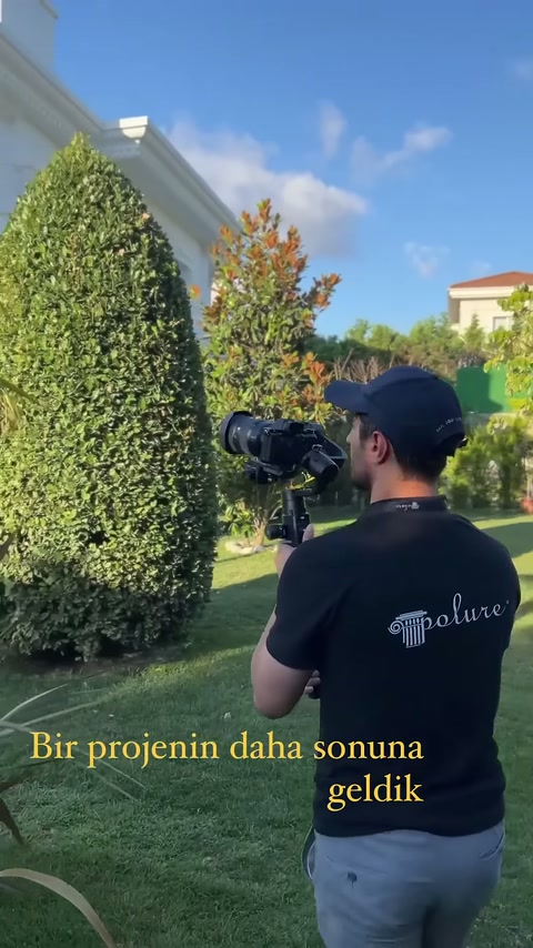 Peyzajlı alanda kameraman, villanın uzaktan görünen dış cephe süslemelerini çekiyor.