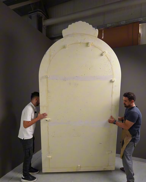 Due artigiani che trasportano il pannello in rilievo di poliuretano grezzo nel laboratorio.