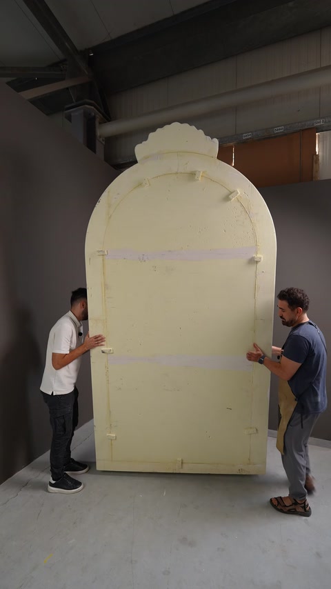 The back of the arched decorative panel during production is examined