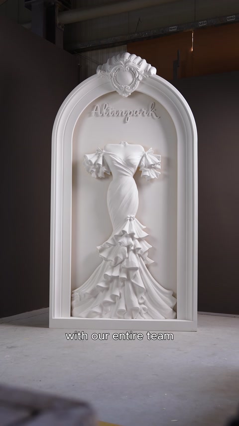 The completed wedding dress relief is displayed inside the arched decorative panel