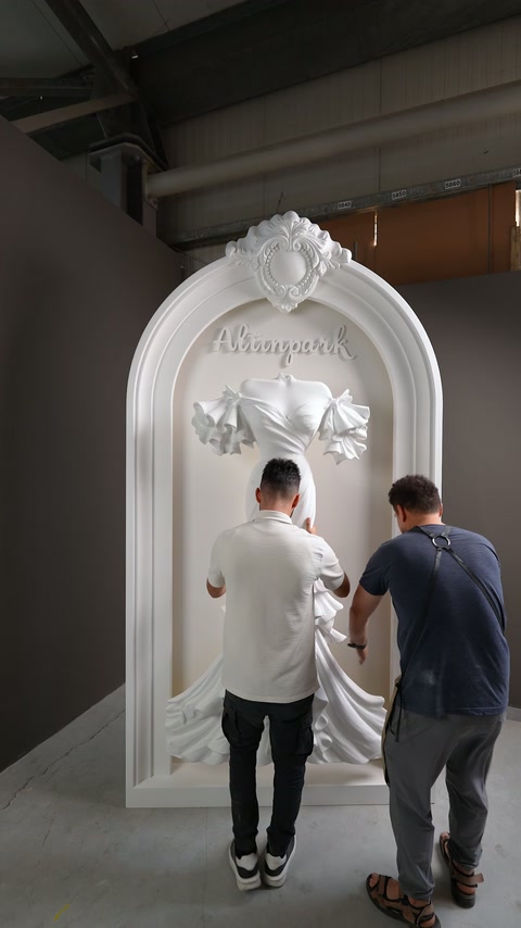 Il rilievo a forma di abito da sposa viene collocato sulla superficie della nicchia da due artigiani