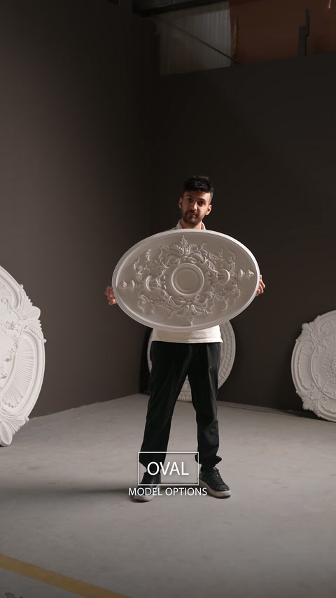 Il presentatore tiene un medaglione da soffitto ovale con un equilibrato ornamento floreale.