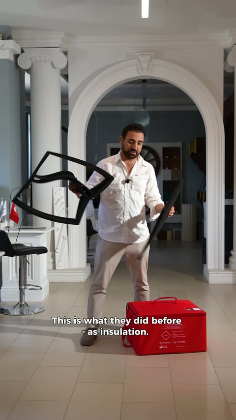 Open frame-shaped black insulation piece is examined in presenter's hand.