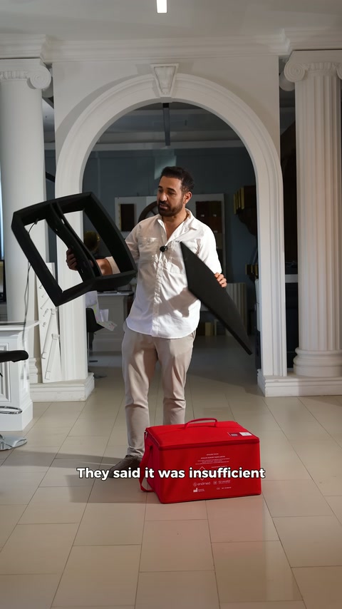 Presenter holds frame-shaped black piece at chest height.