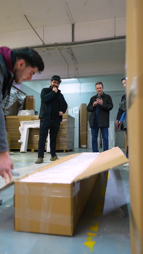Un lungo pezzo di profilo decorativo è esaminato su un tavolo nell'area di fabbrica