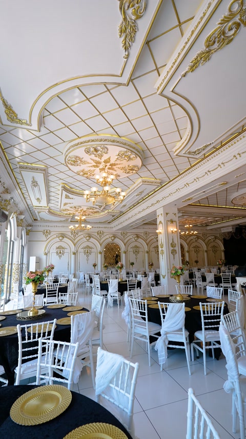 Circular ceiling cornice frames chandeliers above the furnished wedding hall