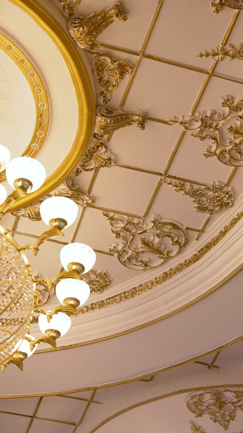 Curved cornices and ornate gold reliefs surround ceiling light fixtures