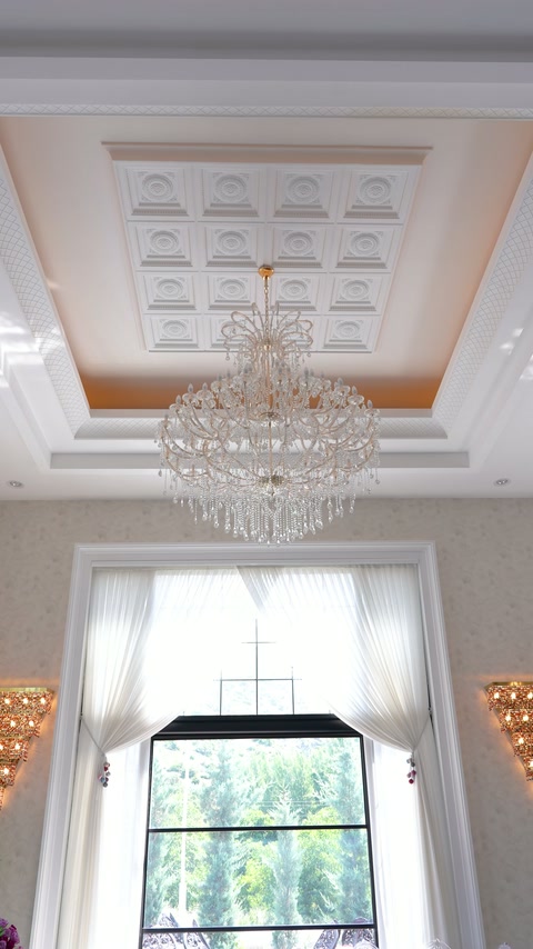 Crystal chandelier hangs beneath a geometric recessed ceiling centerpiece