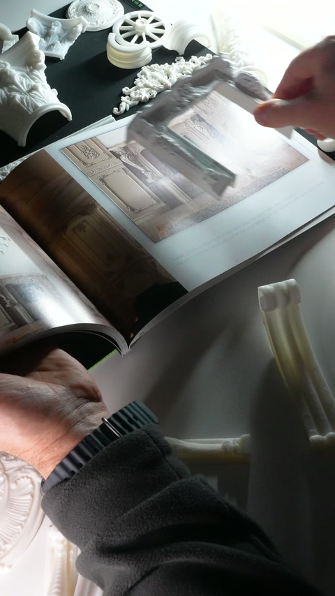 A finger indicates the ceiling treatment shown in the open catalogue.