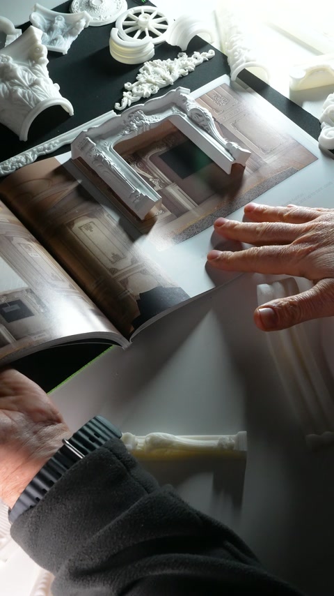 Hands align the decorative frame sample with the printed room design.