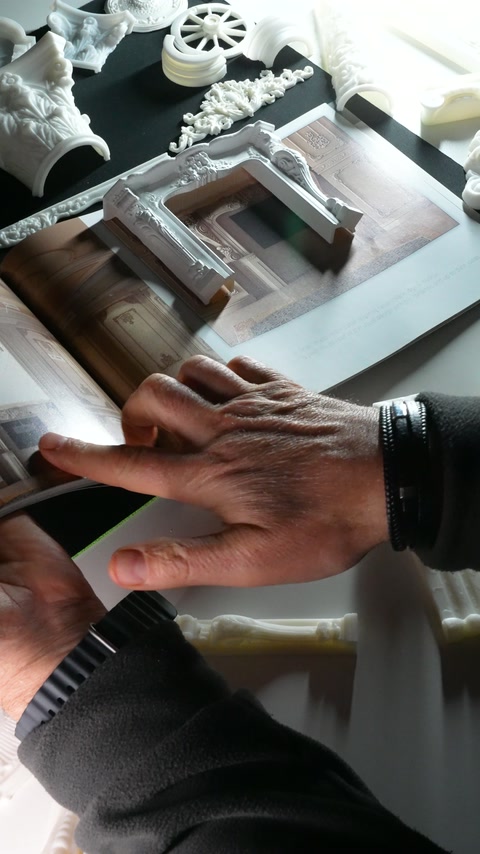 A hand steadies the sample while comparing its carved corner details.