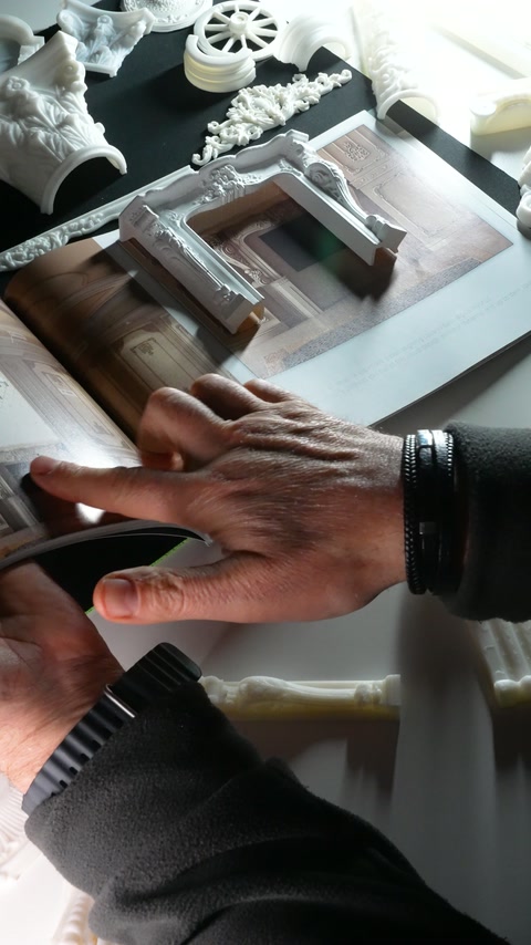 Fingers trace the printed architecture beneath the raised decorative frame.