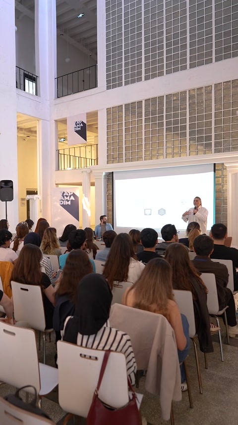 Gli studenti seguono insieme una presentazione di architettura in una sala con soffitto alto