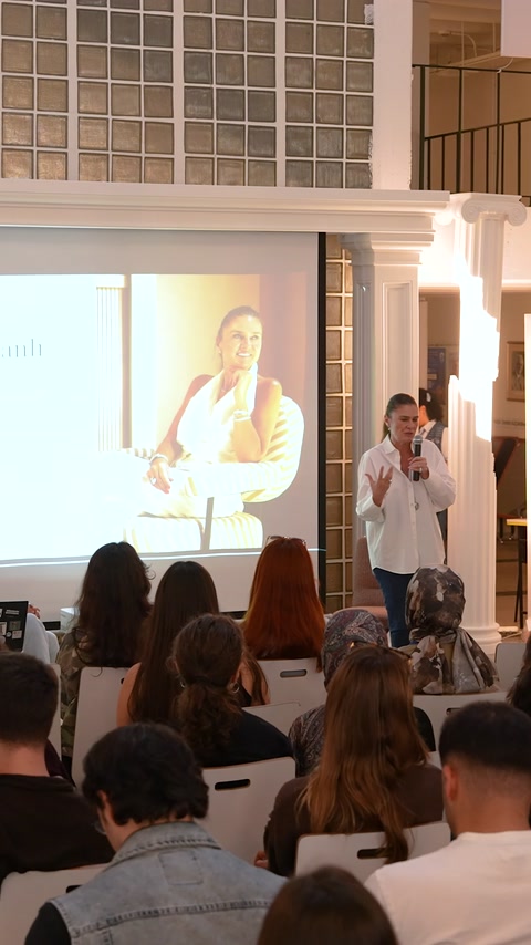 Un relatore tiene una presentazione agli studenti su un palco circondato da colonne decorative