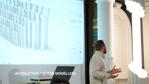 Il presentatore mostra con la mano la superficie di un alto fusto di colonna illuminato.