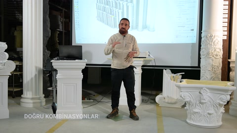 Basamenti di colonne e capitelli decorativi sono esposti attorno al presentatore.