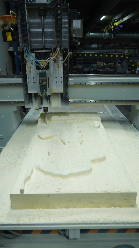 Una macchina CNC lavora la superficie di un pannello decorativo in rilievo