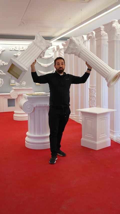 Presenter displays arch and column pieces with both hands in the showroom