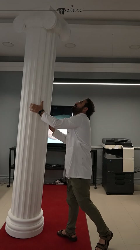 Craftsman inspects the surface of a long fluted column shaft in the showroom