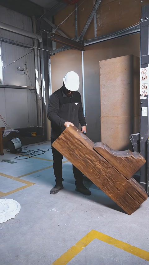 Un lungo elemento di trave decorativa con texture effetto legno viene trasportato a mano