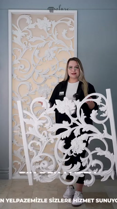 Il pannello bianco decorato con elementi botanici viene presentato davanti alla parete espositiva