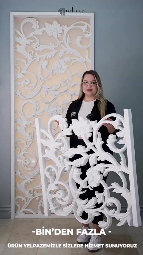 Il presentatore tiene il pannello decorativo con densi motivi di foglie davanti al corpo