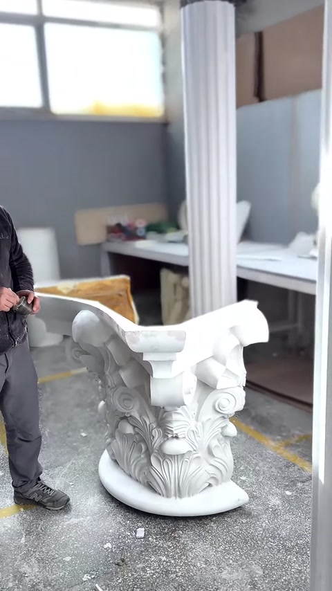 A white Corinthian column capital is displayed with its volutes and corner projections.