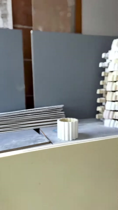 Numerous small decorative pieces are stacked on the production workbench.