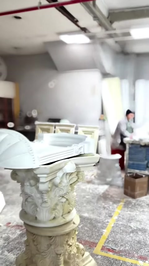 Column capitals, fluted shafts, and decorative pieces are seen together in the workshop.