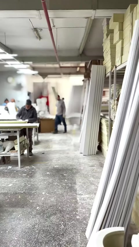 Long fluted column shafts are stacked upright in the production area.