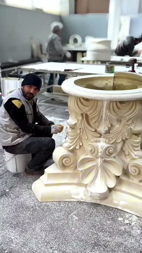Capitello corinzio di colore beige con motivi acanto è posizionato sul banco da lavoro.