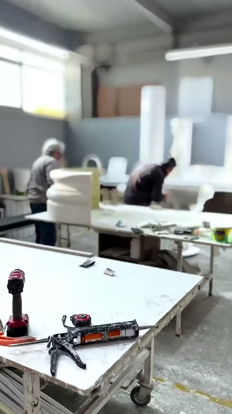 Due maestri lavorano la produzione ai tavoli circondati da parti di colonna.