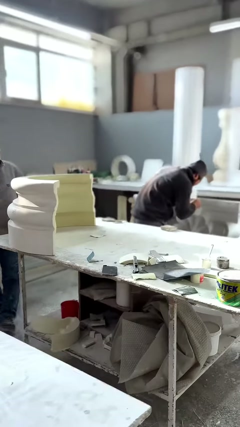 Maestro si piega su una parte di colonna decorata al lungo tavolo da lavoro.