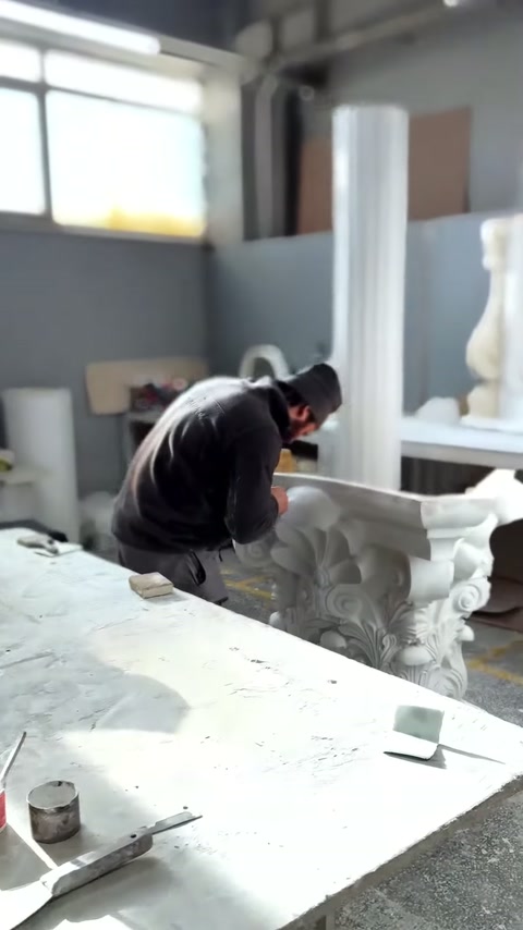 Maestro esegue lavori di finitura sulla parte superiore del capitello corinzio bianco.