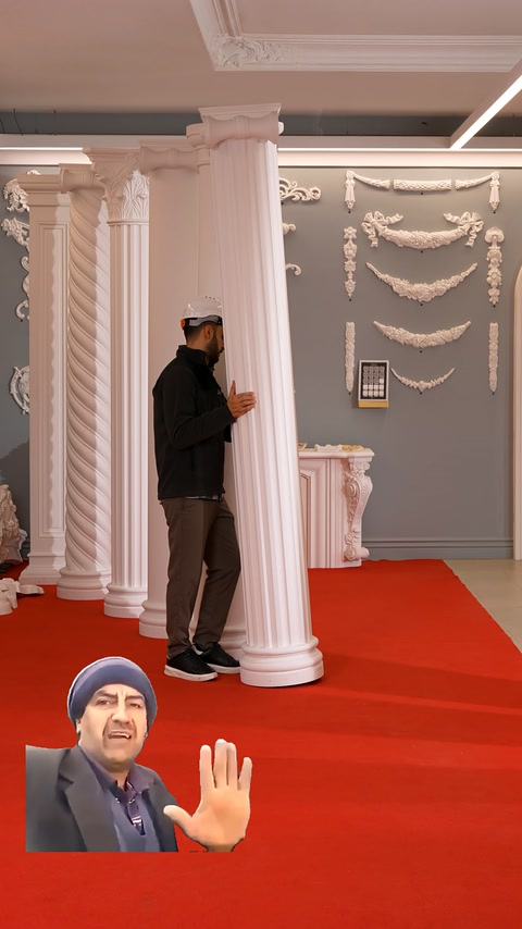 Una colonna rotonda scanalata viene esaminata davanti a decorazioni murali ornamentali.
