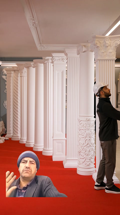 Multiple columns with different capital designs stand side by side in the exhibition hall.