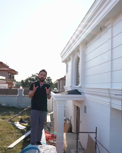 Presentatore in piedi davanti alla facciata bianca in poliuretano completata della villa
