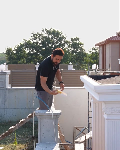 Operaio che rifinisce il capitello di una colonna in poliuretano sul tetto durante l'applicazione
