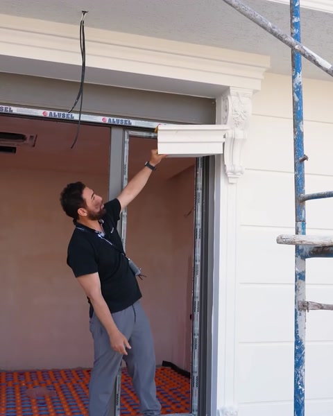 Installatore che monta una cornice sopra un'apertura finestra sul ponteggio