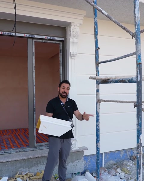 Uomo che trasporta un pezzo di modanatura vicino alla finestra durante l'installazione