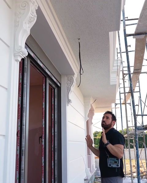 Operaio che si allunga per installare un dettaglio di mensola in cima alla colonna