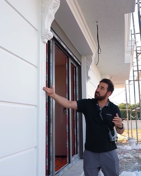 Presentatore che indica il rivestimento murale completato vicino all'ingresso della villa