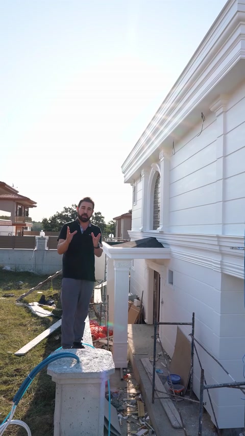Presenter standing in front of finished white polyurethane villa facade