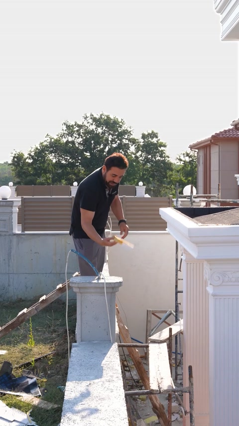 Worker finishing polyurethane column cap on rooftop during application