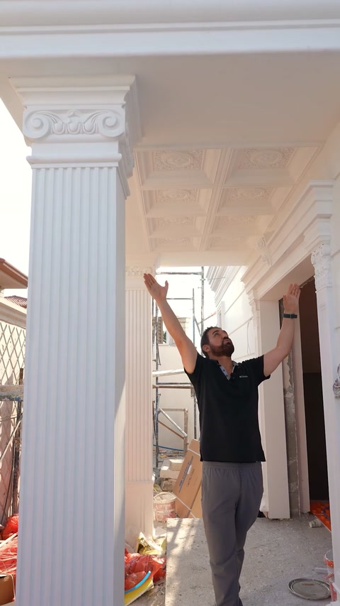 Man reaching up to inspect fluted pilaster on scaffolded facade