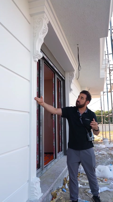 Presenter pointing at finished wall covering near villa entrance