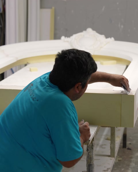 Operaio che carteggia a mano il componente di arco per la finitura finale