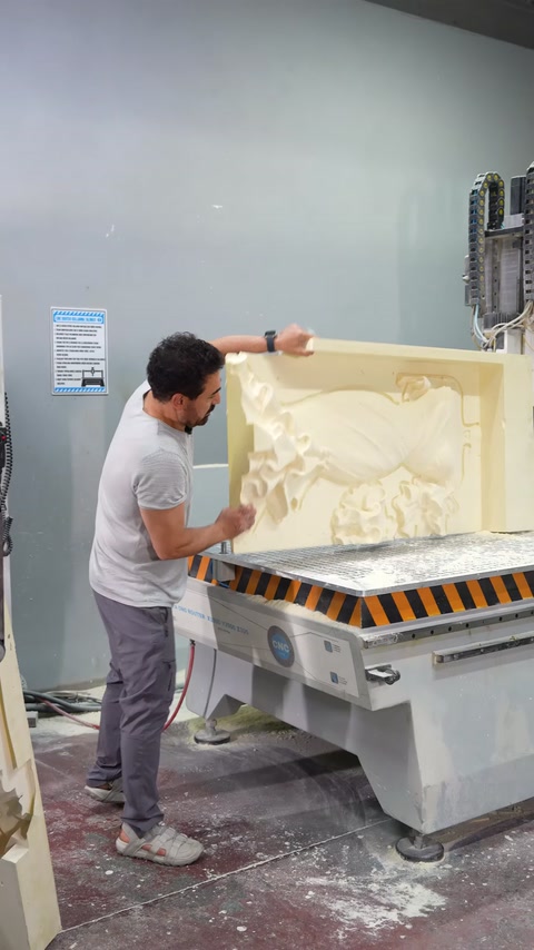 A craftsman inspects the surface of the large relief mold on the CNC machine.